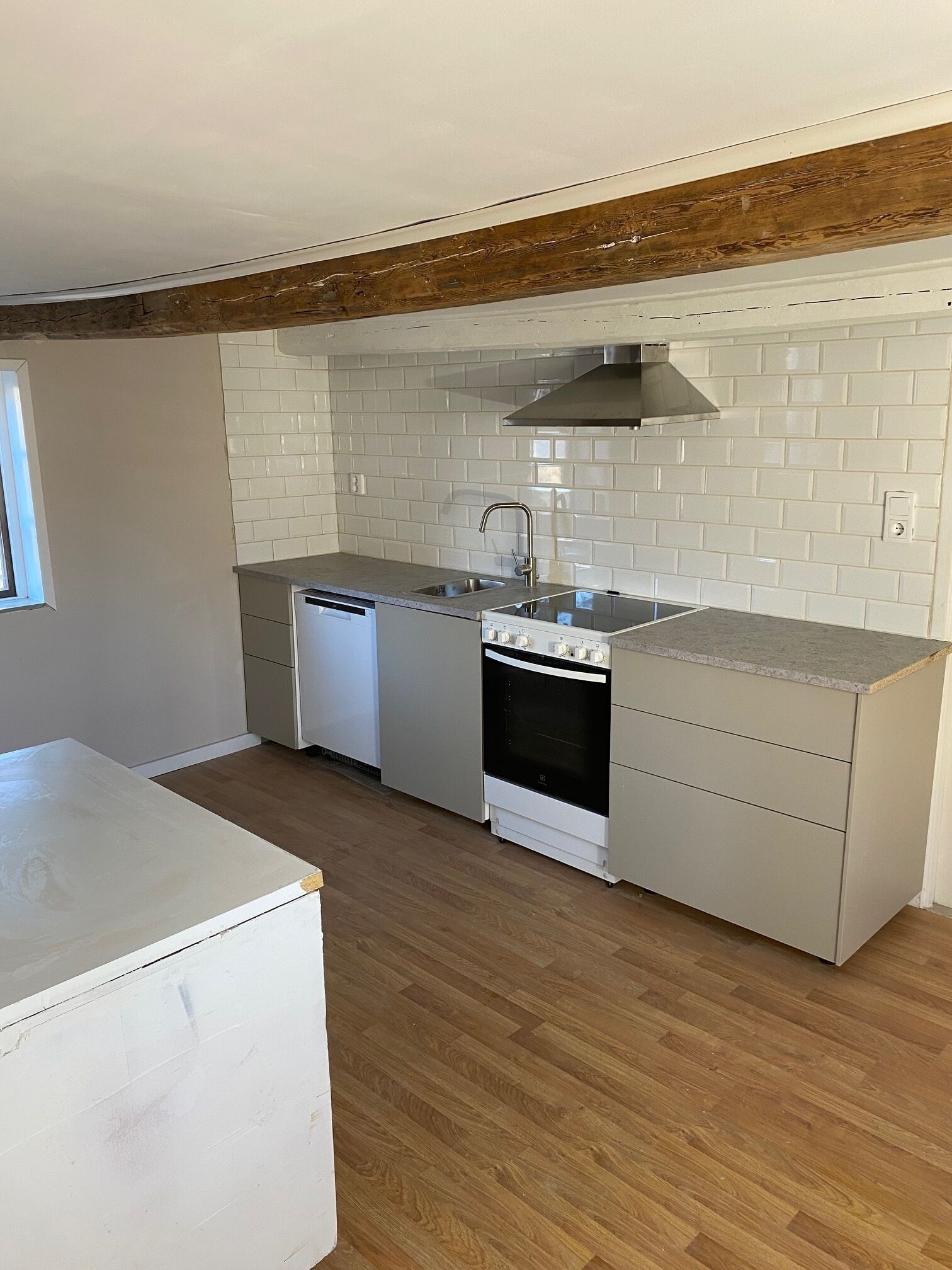 A kitchen with white cabinets, a stainless steel sink, a built-in oven, and a dishwasher.