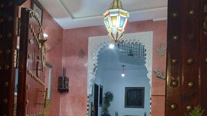 An interior hallway with a patterned floor, a traditional wooden door, and a hanging light fixture. - Riad Zaid (Marrakech)