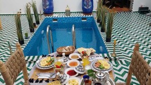 A dining area with a pool, surrounded by potted plants and traditional decor. - Riad Zaid (Marrakech)