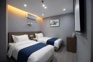 Habitación de hotel con dos camas, una mesita de noche pequeña, aire acondicionado instalado en la pared, una obra de arte en marco y un espejo.