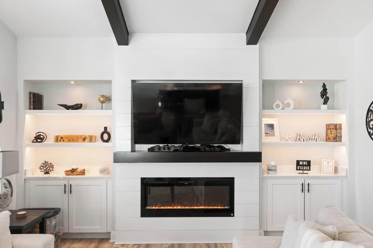 Una sala de estar moderna con chimenea, televisor y estanterías decoradas.