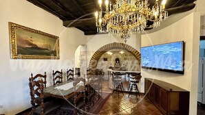 A dining area with a chandelier, a painting, a stone arch, a TV, and a bar. - The Tower "UnaNotteaCasaMia" (Sacrofano)
