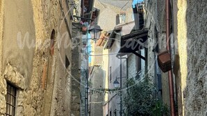 A narrow cobblestone street flanked by historic stone buildings with a clock tower in the background. - The Tower "UnaNotteaCasaMia" (Sacrofano)