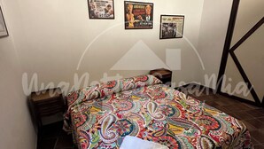 A bedroom with a colorful bedspread, a tiled floor, and several framed posters on the wall. - The Tower "UnaNotteaCasaMia" (Sacrofano)
