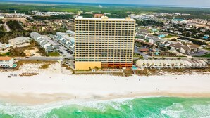 Hotel alto com um pátio central, situado perto de uma praia e vista para o oceano.