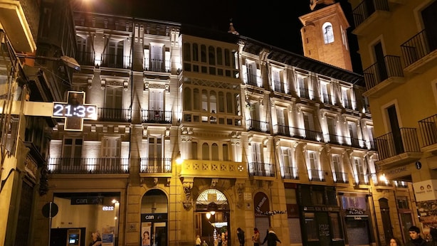 A multi-story building with illuminated balconies and a clock tower.