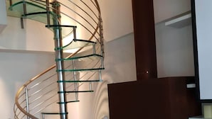 A modern interior with a spiral staircase, a fireplace, and two white statues.