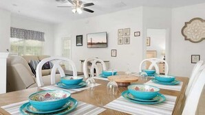 A dining room with a wooden table set for four, surrounded by white chairs.