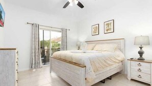 A bedroom with a bed, a nightstand, a ceiling fan, and a window with curtains.