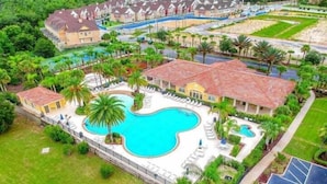 A resort with a large central swimming pool, multiple guest villas, and lush landscaping.