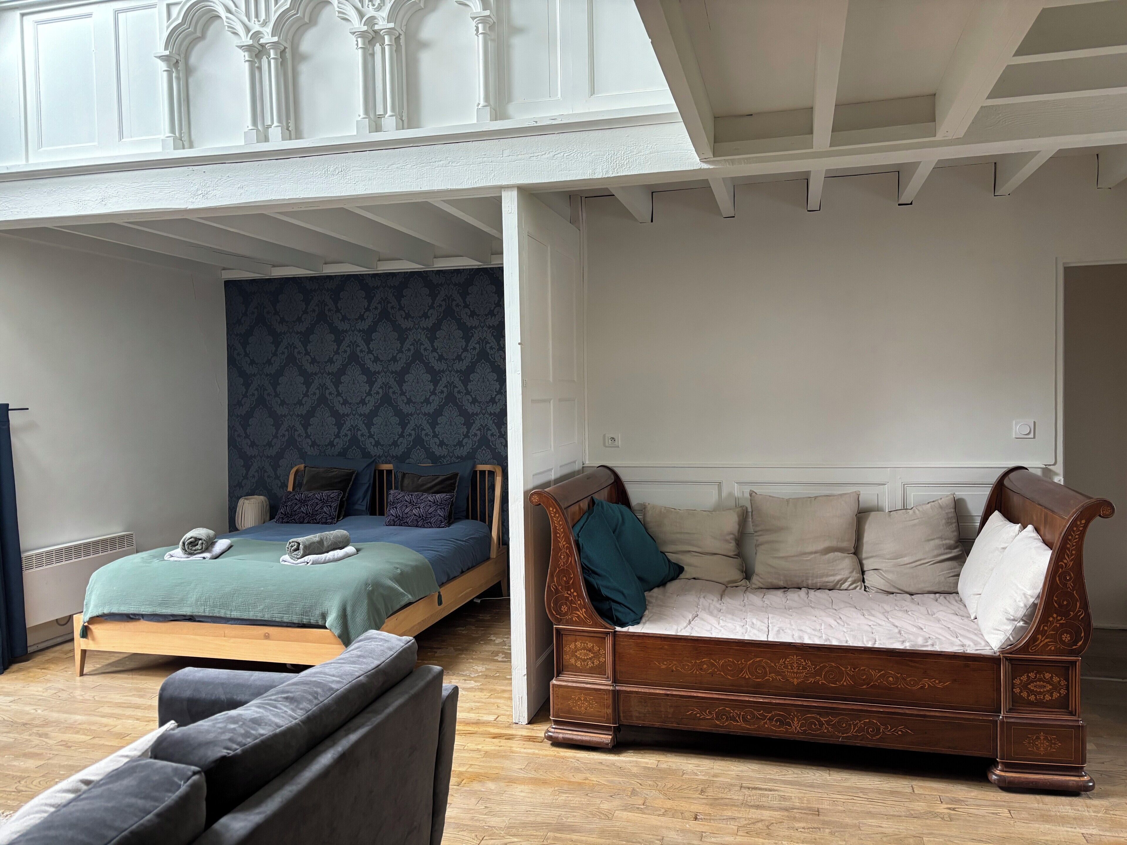 Una habitación con una cama, un sofá de madera y una ventana con vista al cielo.