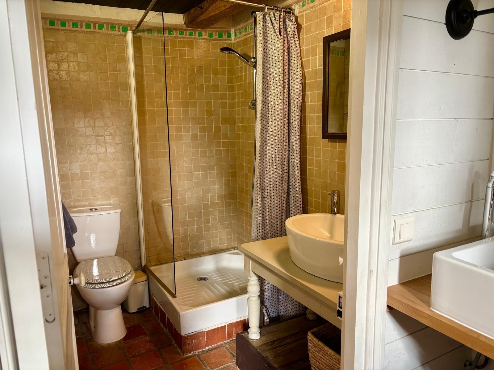 A bathroom with a toilet, a shower with a glass door, and a sink with a mirror above it.