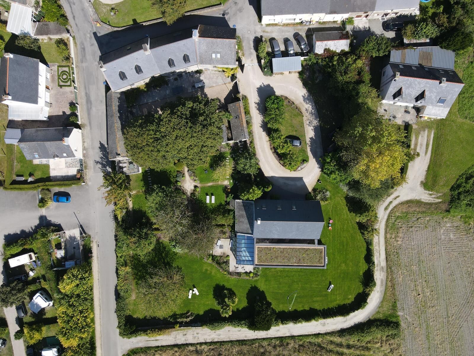 Vue aérienne d’un quartier résidentiel avec des maisons, une piscine et un grand espace ouvert.