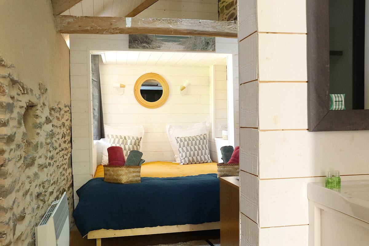 Una habitación con cama, espejo redondo y ventana.