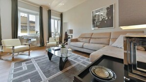 A modern living room with a sofa, armchairs, a glass coffee table, and a dining area with a table and chairs. - Luxurious 6-Bedroom Apartment in a Historic Palazzo with Panoramic Terrace





 (Firenze)