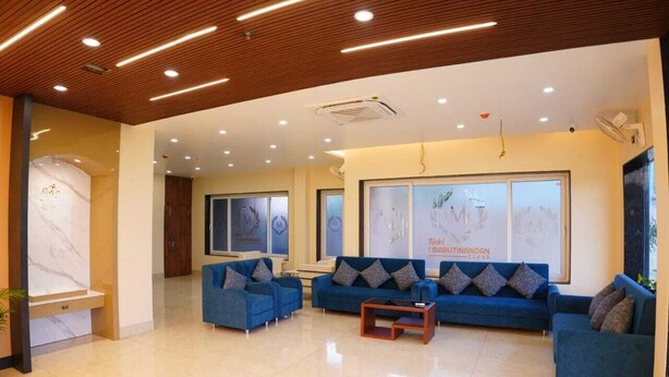Eine moderne Lobby mit blauen Sofas, einem Marmor-Rezeptionstresen und gerahmten Kunstwerken an den Wänden.
