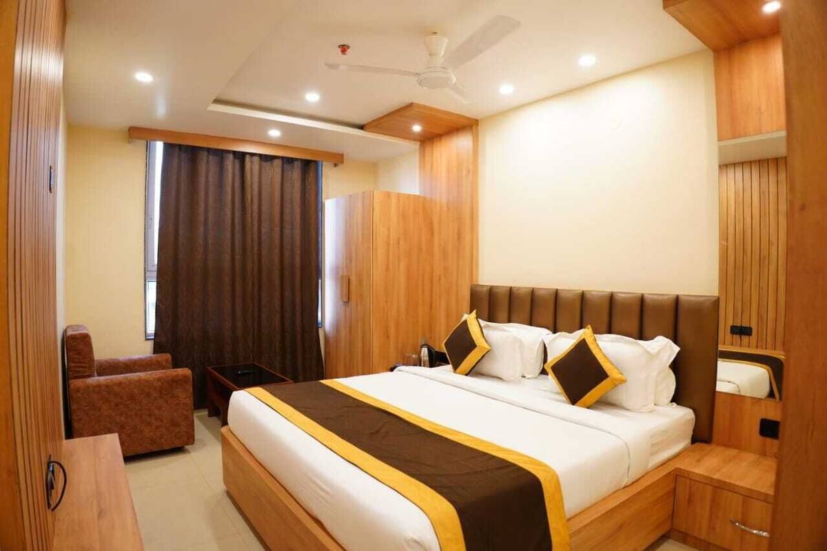 A hotel room with a large bed, a desk, a chair, and a ceiling fan.