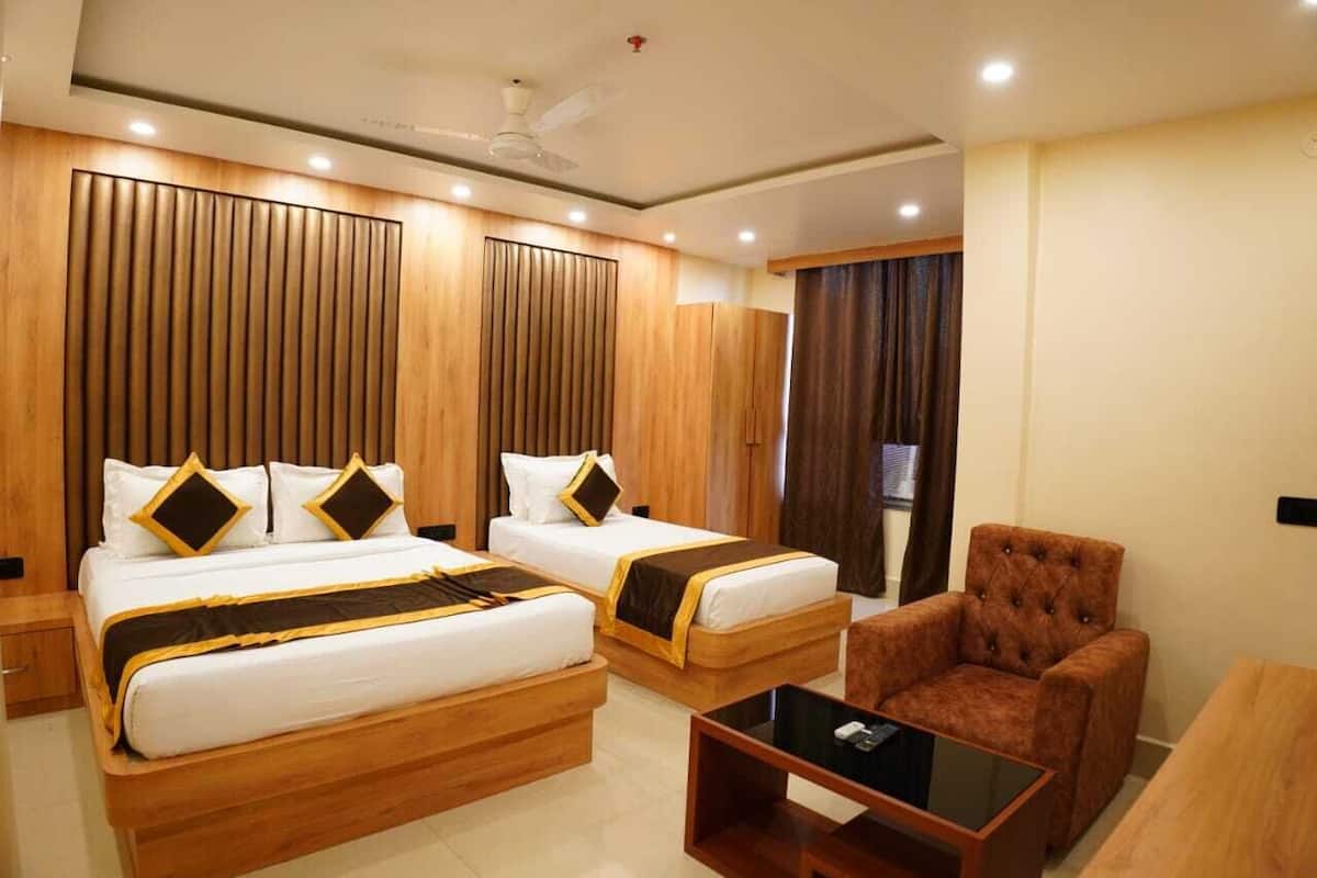 A hotel room with two beds, a sofa, a coffee table, and a ceiling fan.