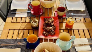 A wooden table set for breakfast with various food items, drinks, and utensils. - Maison d'hôtes La Bellours (Cahors)