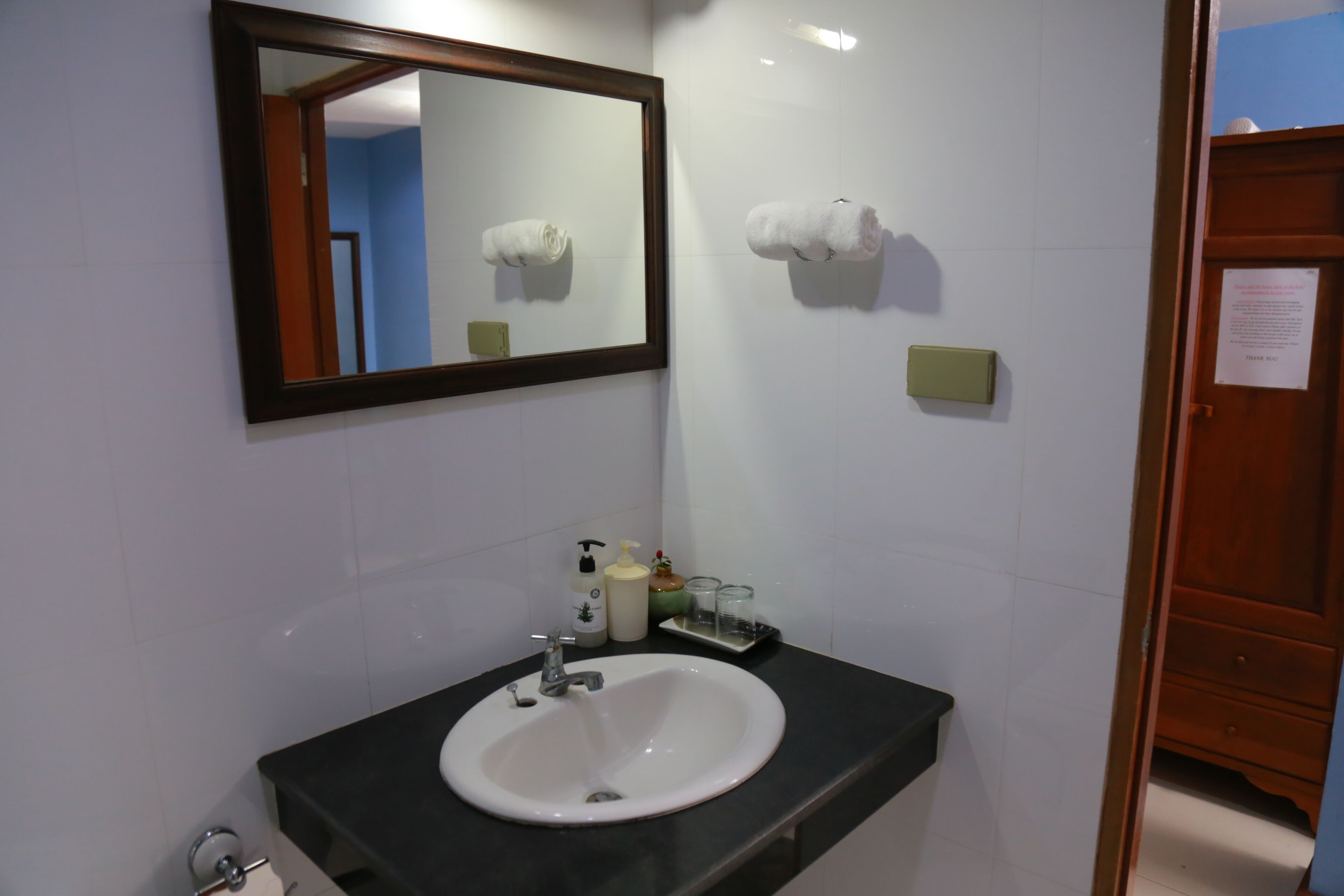 A bathroom with a white sink, a mirror, and two towels on the wall.