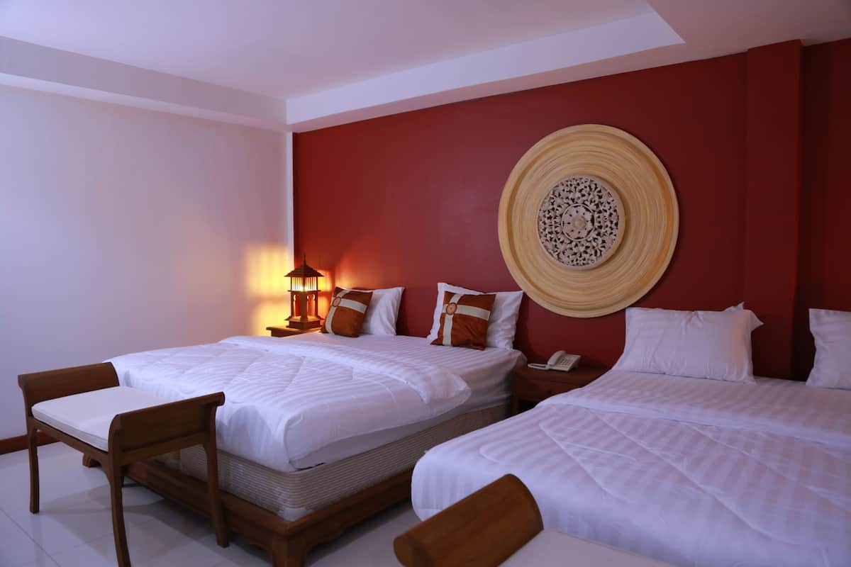 Une chambre d’hôtel avec deux lits, une table de chevet, une lampe et un élément décoratif mural.