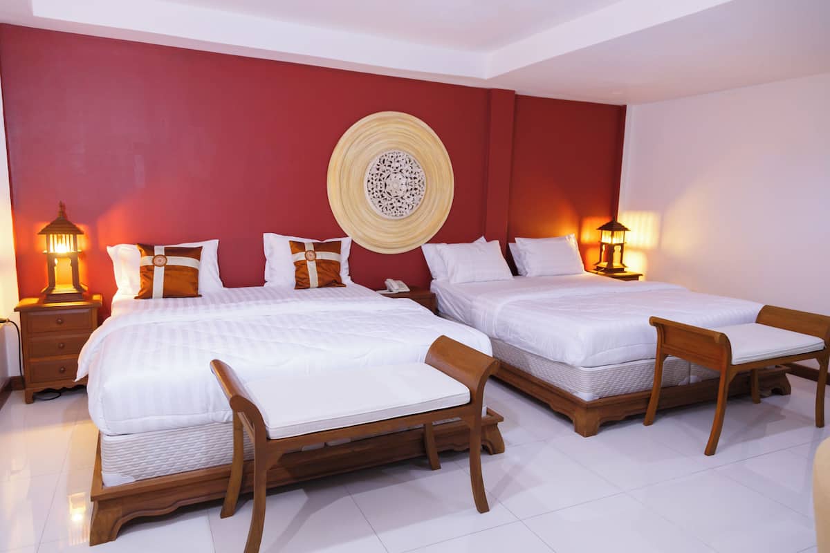 Une chambre d’hôtel avec deux lits, des têtes de lit en bois, du linge de lit blanc, des murs rouges et des œuvres d’art décoratives.