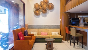 A modern living area with a sofa, chairs, a coffee table, and a wall-mounted decorative piece. - UPAR Hotels Silom (Bangkok)