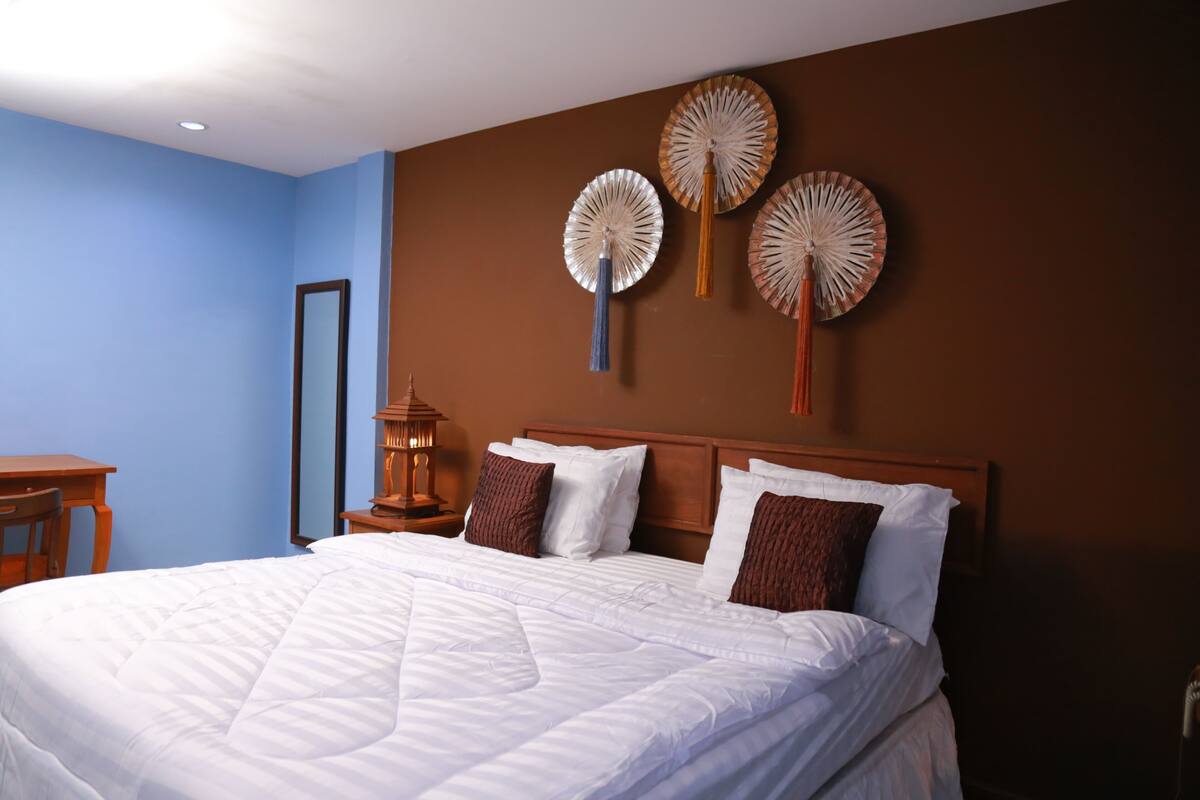 Un lit bien fait, avec du linge de lit blanc, une tête de lit en bois et trois éléments décoratifs accrochés au mur.