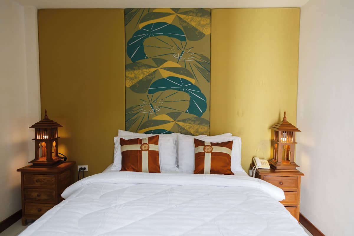 Une chambre d’hôtel avec un lit, deux tables de chevet et un mur orné d’un tableau aux motifs géométriques.