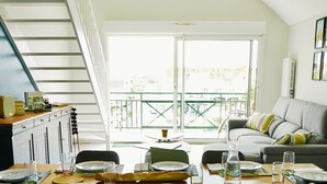 Een eetgedeelte met een tafel voor vier personen, een bank en een trap naar een balkon met uitzicht.