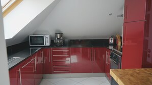 Een moderne keuken met rode kastjes, een magnetron, een koffiezetapparaat en een houten aanrecht.