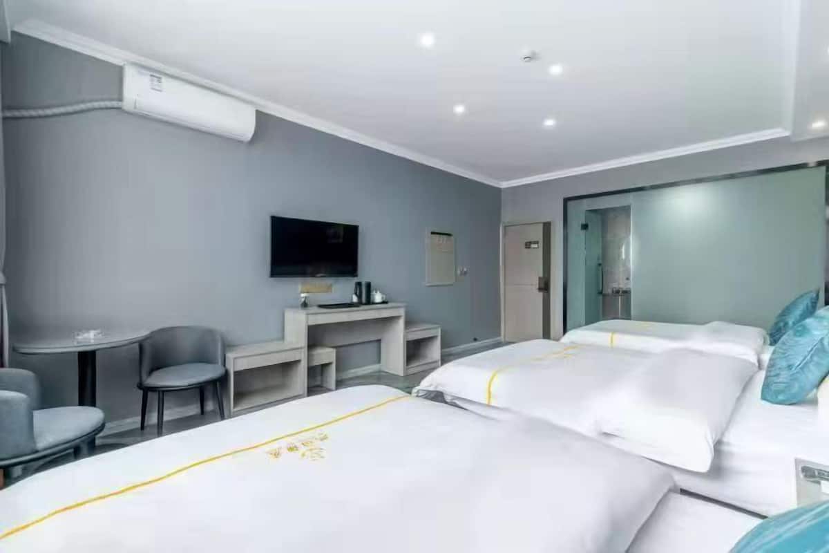 A hotel room with two beds, a desk, a chair, a television, and a minibar.