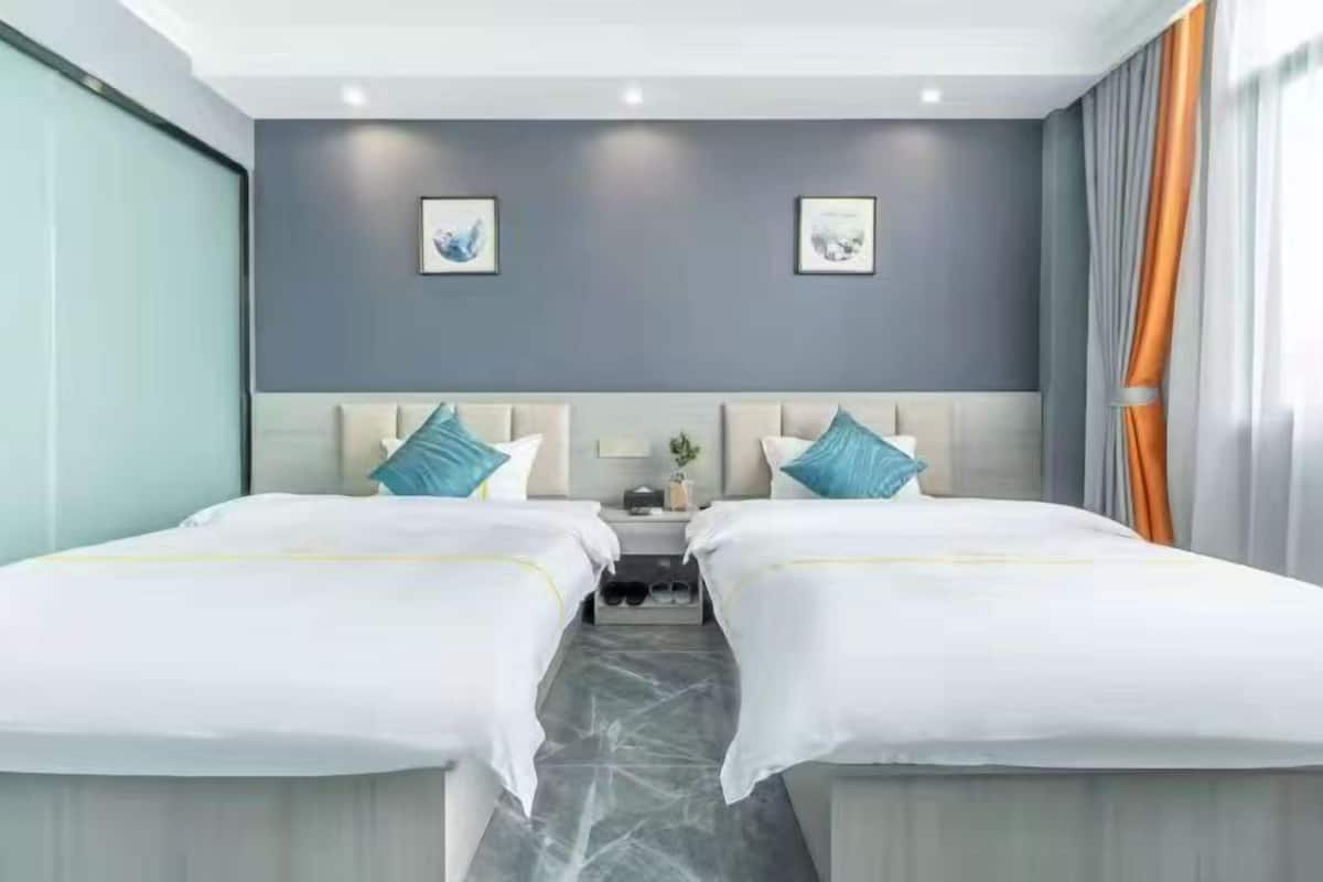 A hotel room with two beds, a nightstand, and a marble floor.
