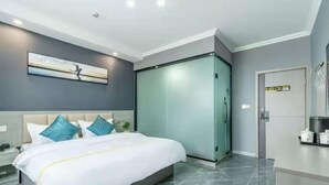 A modern hotel room with a large bed, a nightstand, a wardrobe, and a painting on the wall. - Panda House Hotel (Chengdu)