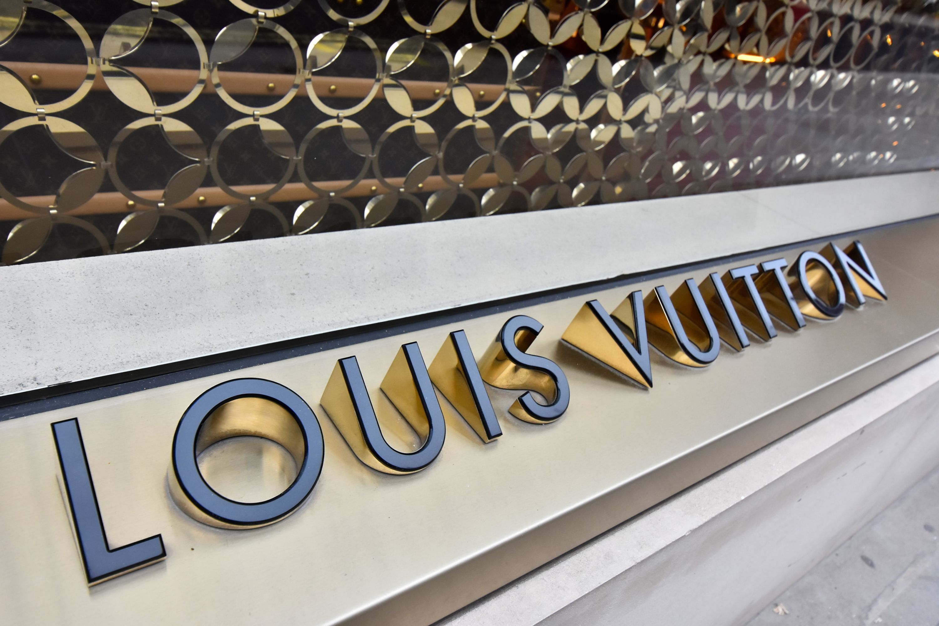 A sign with the text "LOUIS VUITTON" on a metallic surface.