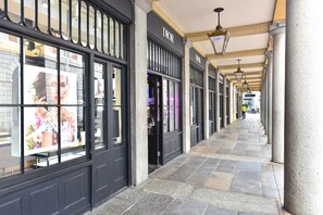 A corridor with storefronts, including a Dior store, and stone flooring. - Earlham Style - 10ts (London)