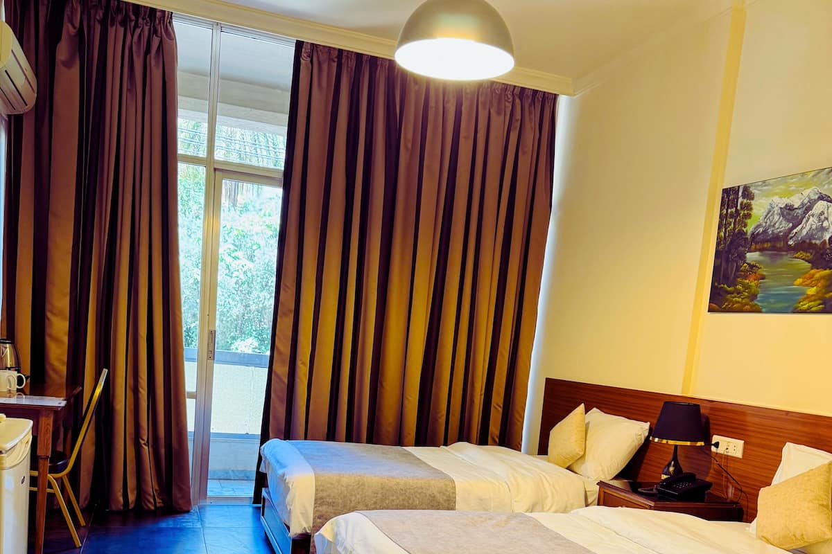 A hotel room with two beds, a desk, and a chair.