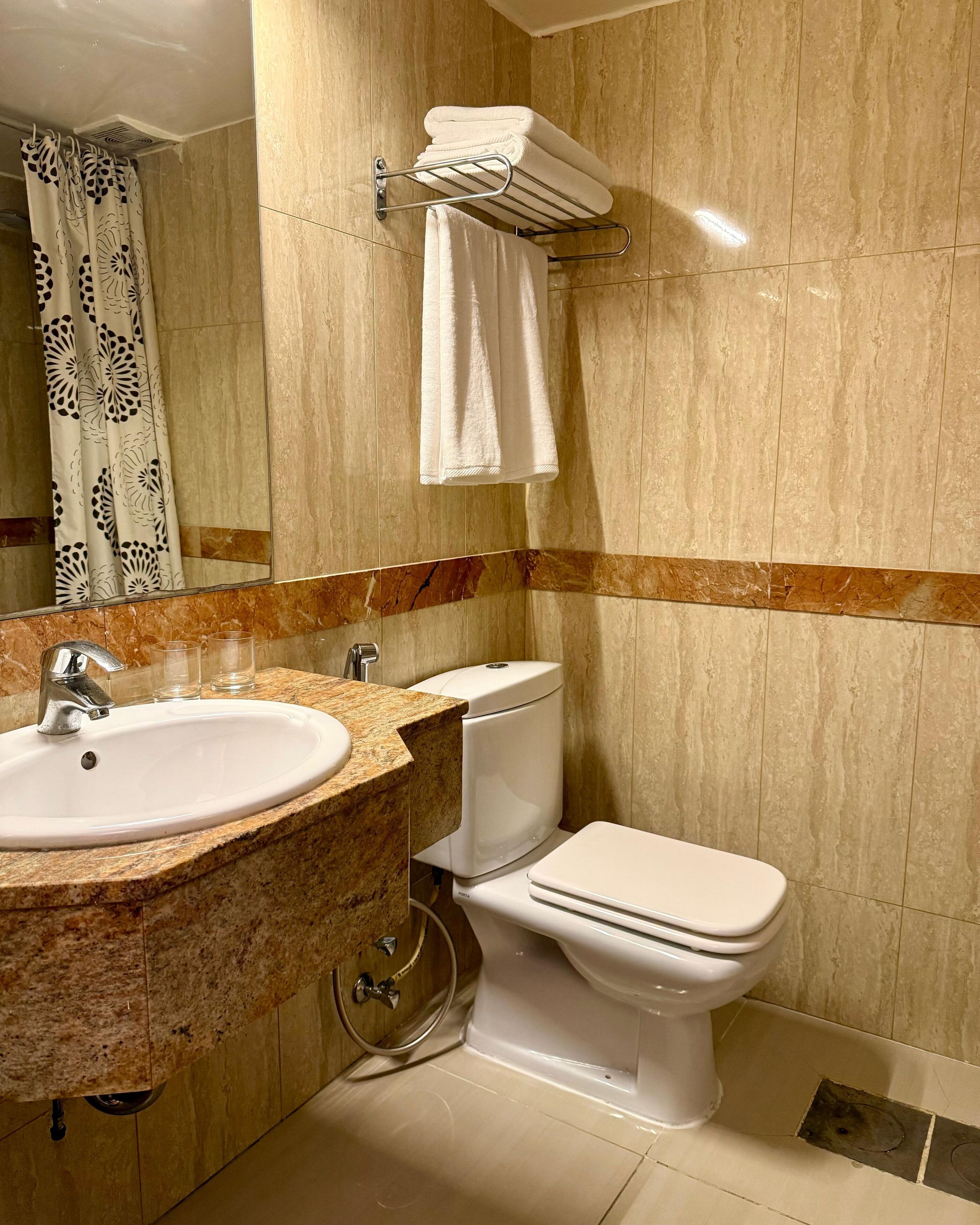 Une salle de bain avec un lavabo en marbre, des toilettes et un porte-serviettes.