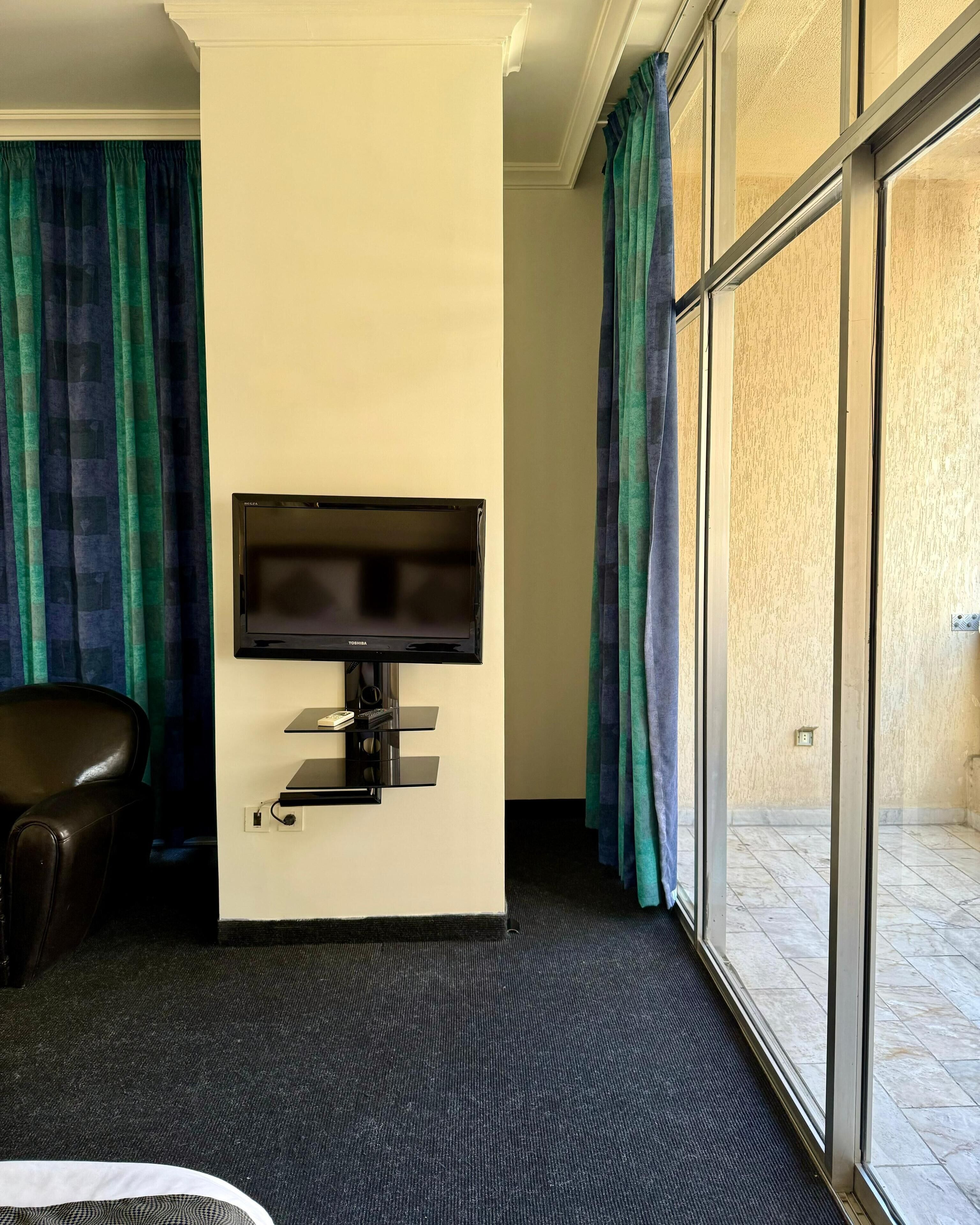 Una stanza con una TV a schermo piatto montata, una poltrona in pelle e vista attraverso una porta in vetro.
