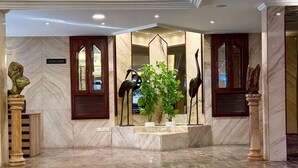 A lobby with marble flooring, a central plant, and decorative sculptures. - Hildon Hotel Beirut (Beirut)