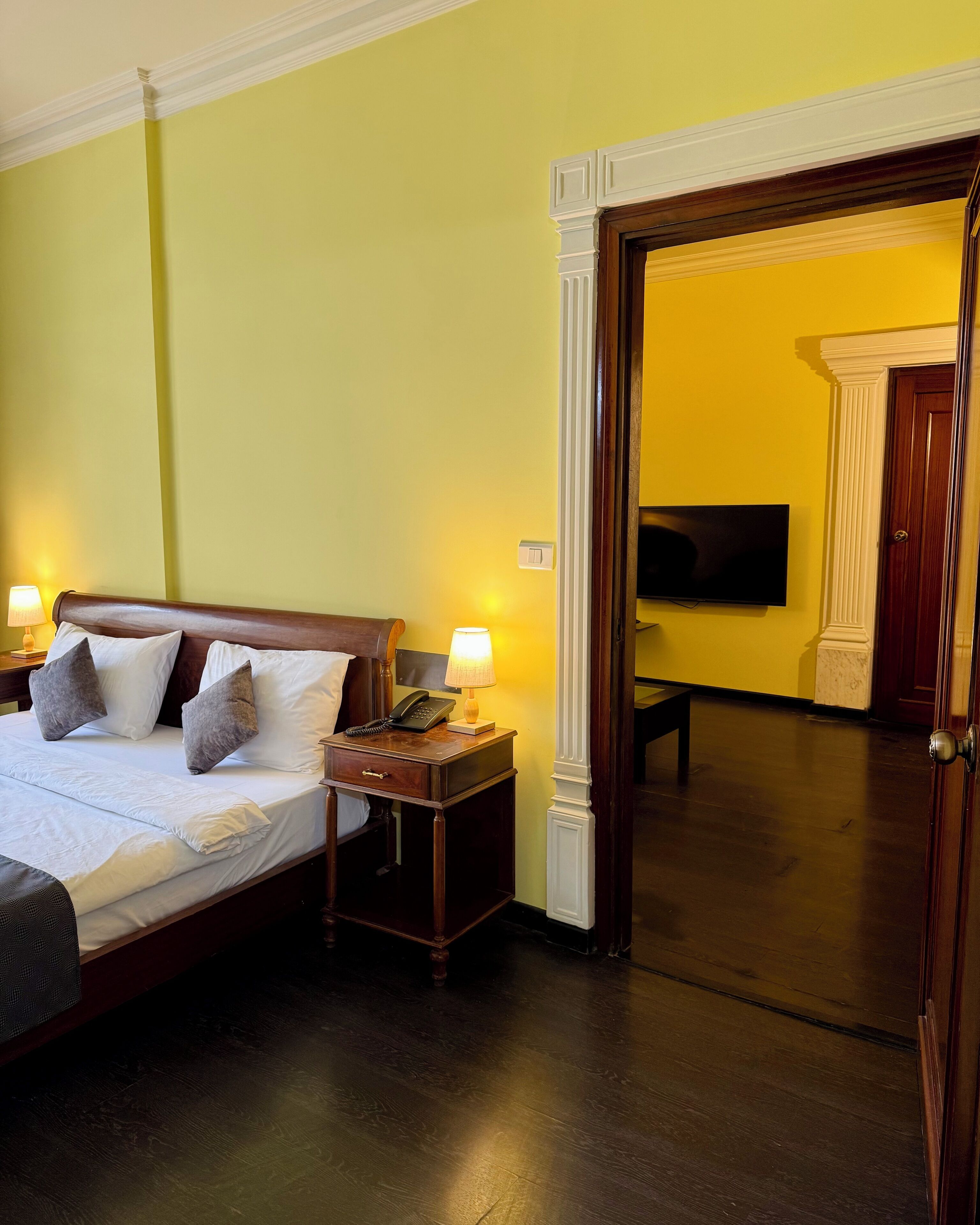 A hotel room with a bed, bedside lamps, a bedside table with a telephone, and a television mounted on the wall.