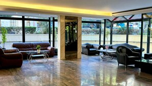 A spacious lobby with a polished marble floor, leather seating, and large windows offering a view of the outdoors. - Hildon Hotel Beirut (Beirut)