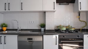 A modern kitchen with white cabinets, a Bosch dishwasher, a gas stove, and a built-in oven. - Cozy flat in Kadıköy 2BR New House (İstanbul)