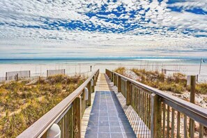 A wooden boardwalk leading to a beach with a clear sky.