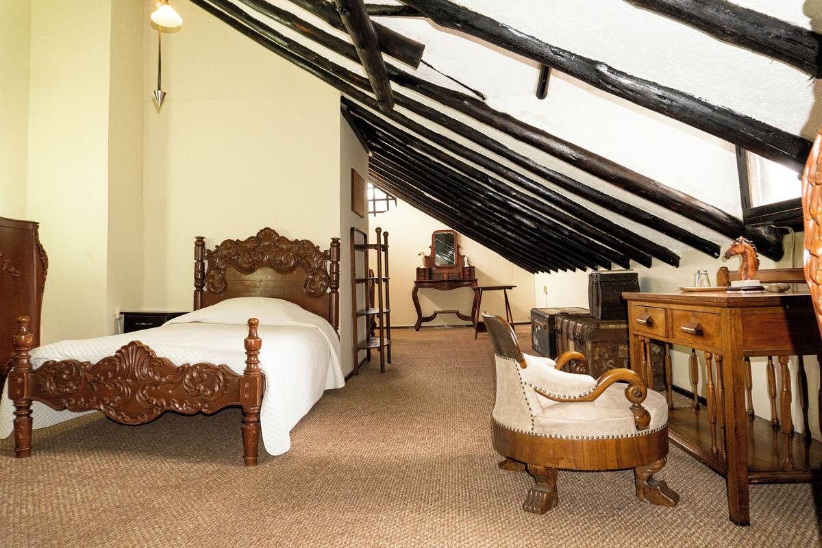 Une chambre à coucher avec un lit en bois, une chaise, un bureau et un miroir.