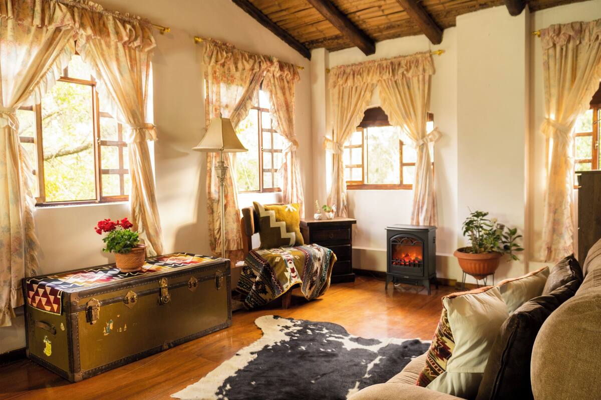 Un salon chaleureux avec une vieille valise, une cheminée et un tapis en peau de vache.