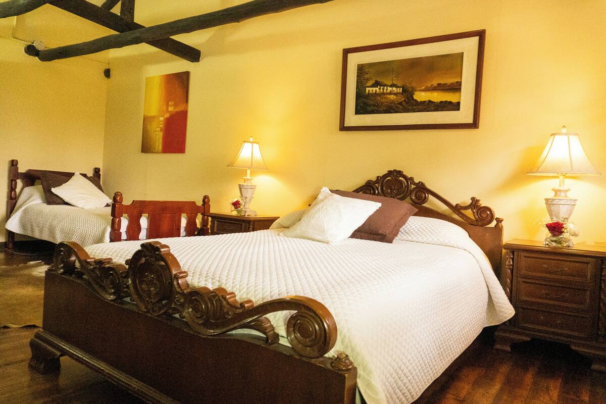 Une chambre à coucher de style traditionnel, avec un lit en bois, deux tables de chevet dotées de lampes et un tableau encadré accroché au mur.