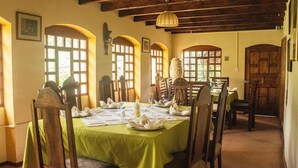 Comedor con mantel verde, sillas de madera y una lámpara de araña.
