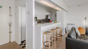 Une cuisine moderne avec des meubles blancs, un dosseret en carreaux noirs et un coin bar avec des tabourets.