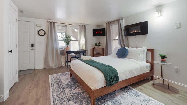 Ein Schlafzimmer mit einem Bett, einem Fernseher, einem Kamin und einem Schreibtisch mit Stuhl.